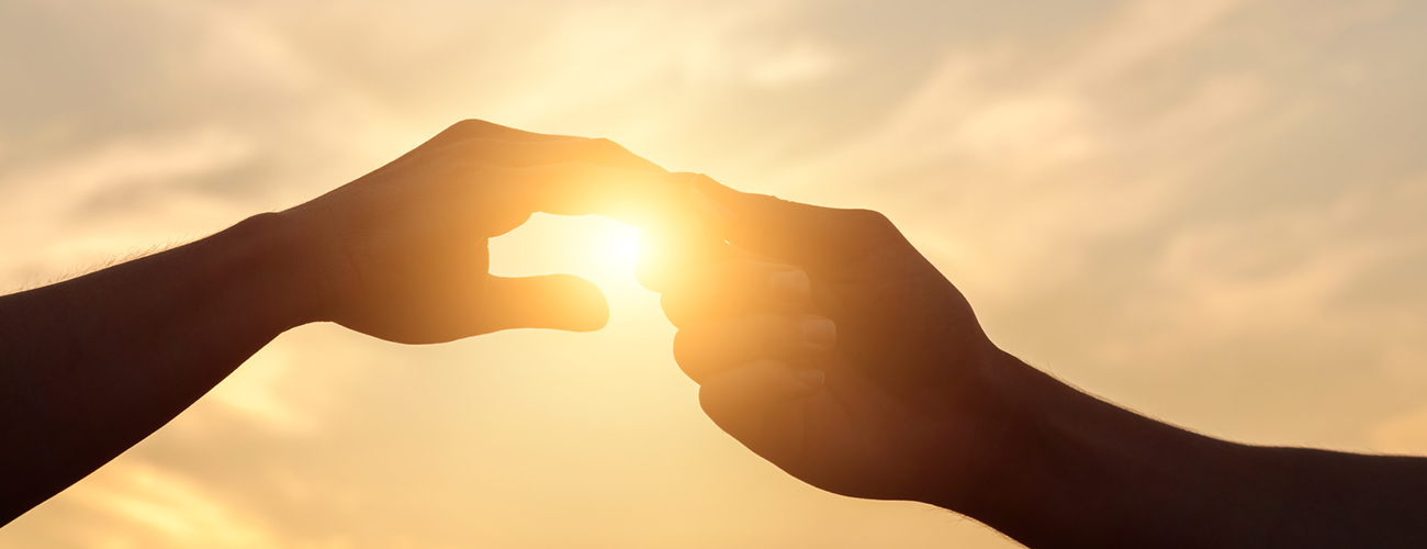 hands holding with sun in background