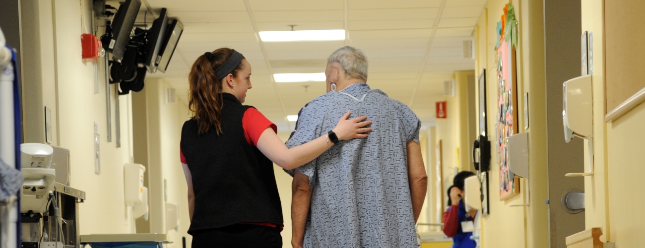 nurse walking down hallway with adult patient